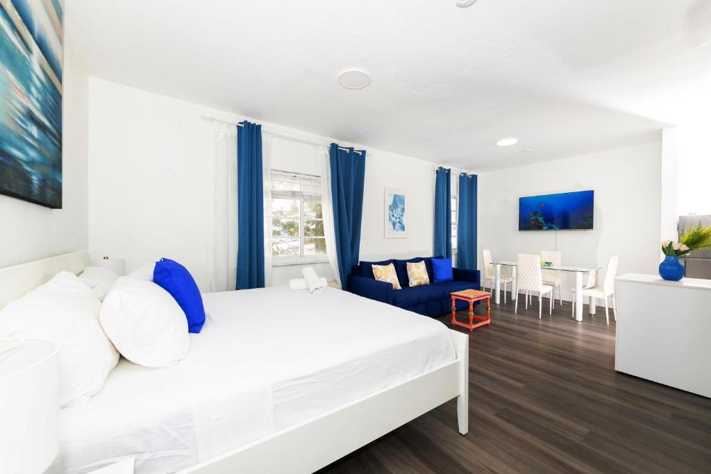 1 dormitorio con 1 cama blanca y comedor en Apartments on Collins, en Miami Beach
