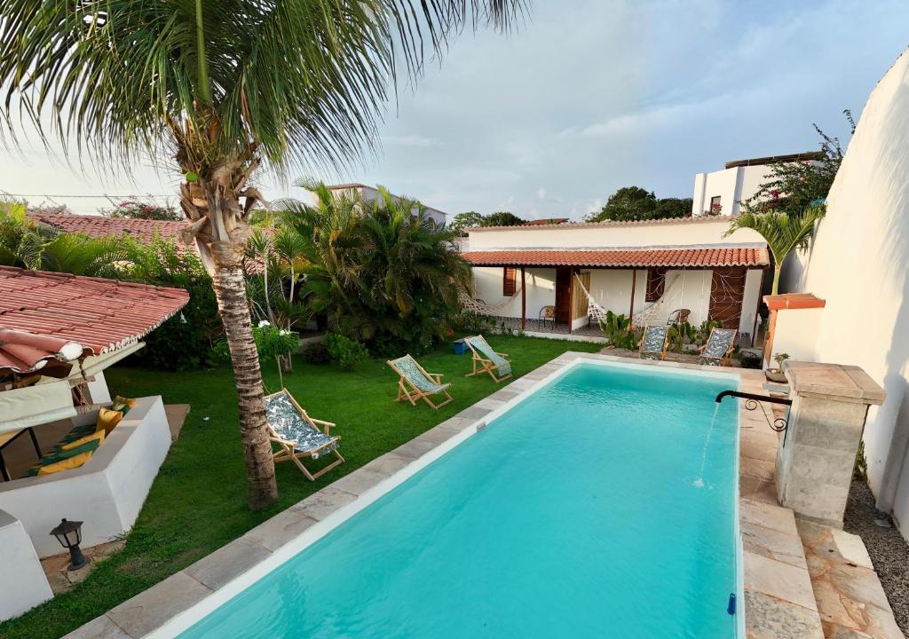 a swimming pool in a yard next to a house at Pousada Casa Do Cocotier in São Miguel do Gostoso