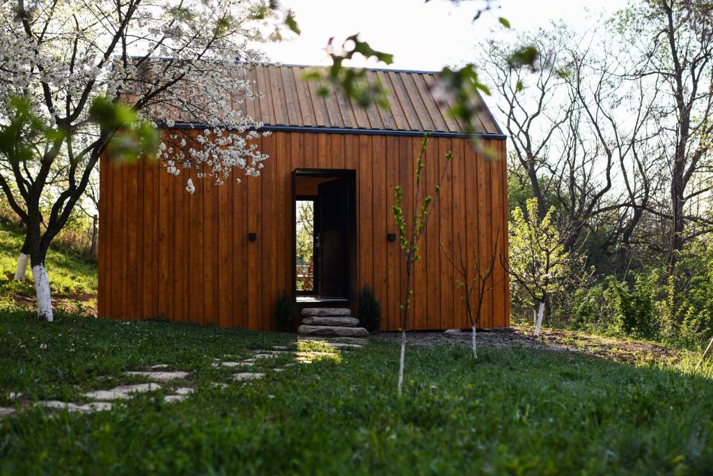 un cobertizo de madera con una puerta en el césped en Căsuța din livadă, en Măneciu