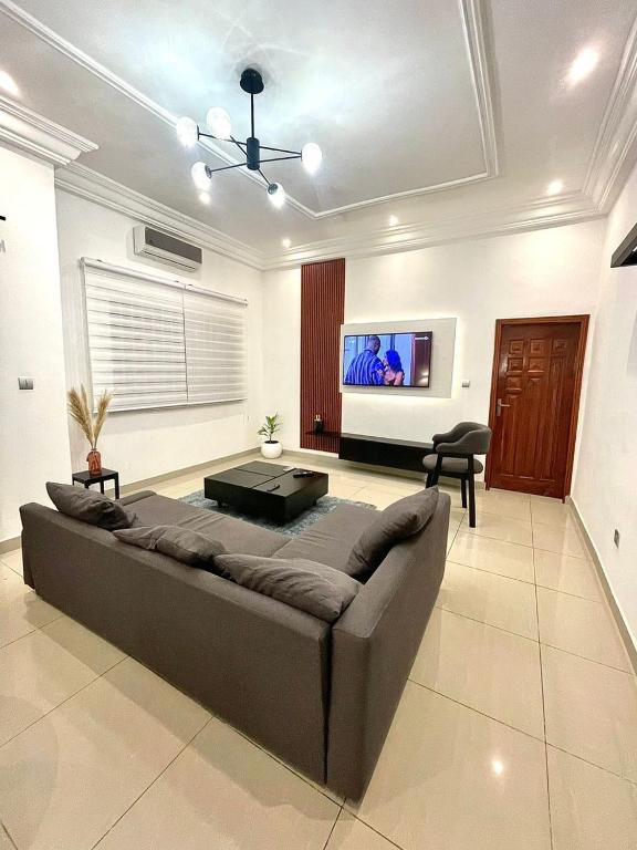 Il comprend un salon doté d'un canapé et d'une télévision à écran plat. dans l'établissement Luxe Cadjehoun, à Cotonou