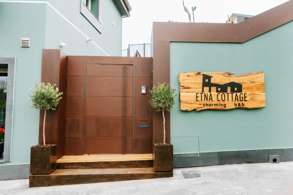Etna Cottage Charming Bed and breakfast في نيكولوسي: باب بني مع علامة على جانب المبنى