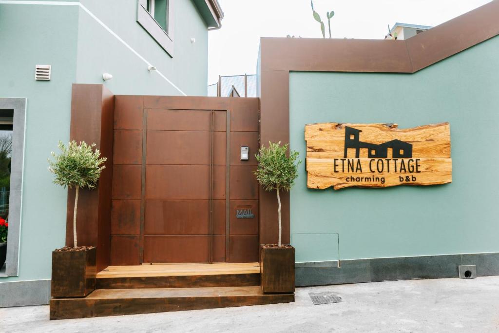 a brown door with a sign on the side of a building at Etna Cottage Charming Rooms in Nicolosi