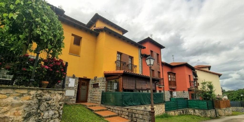 a yellow and orange house with a fence at Casa Las Xanas in Llanes