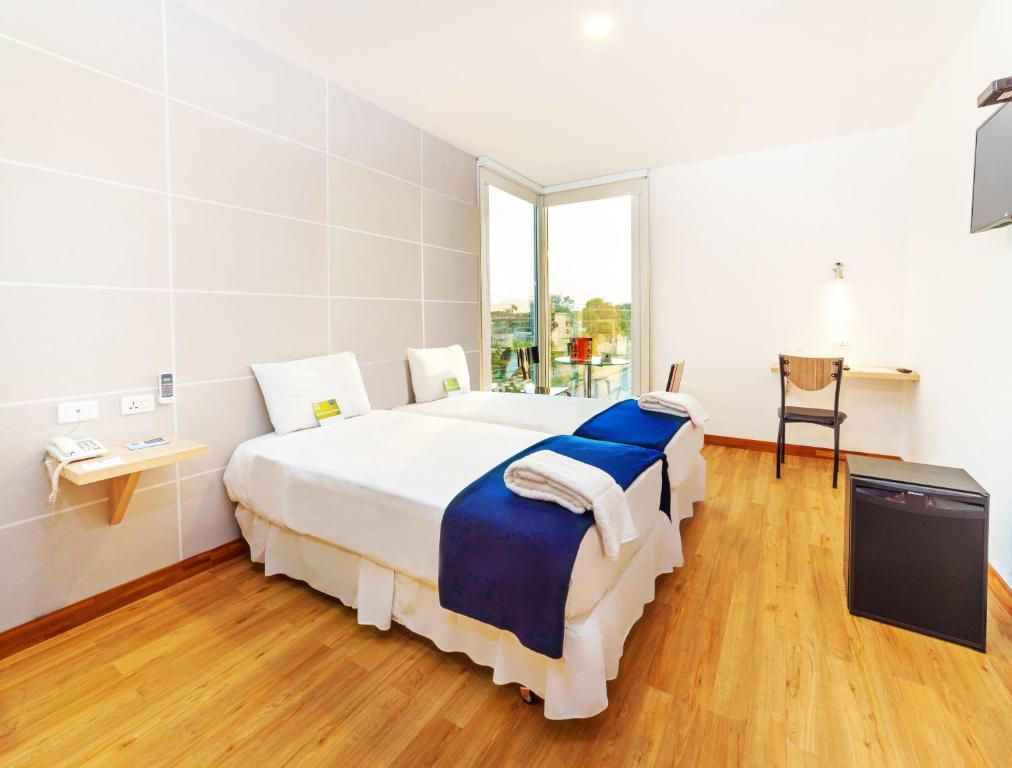 a large white bedroom with a large bed with blue sheets at LP Equipetrol in Santa Cruz de la Sierra