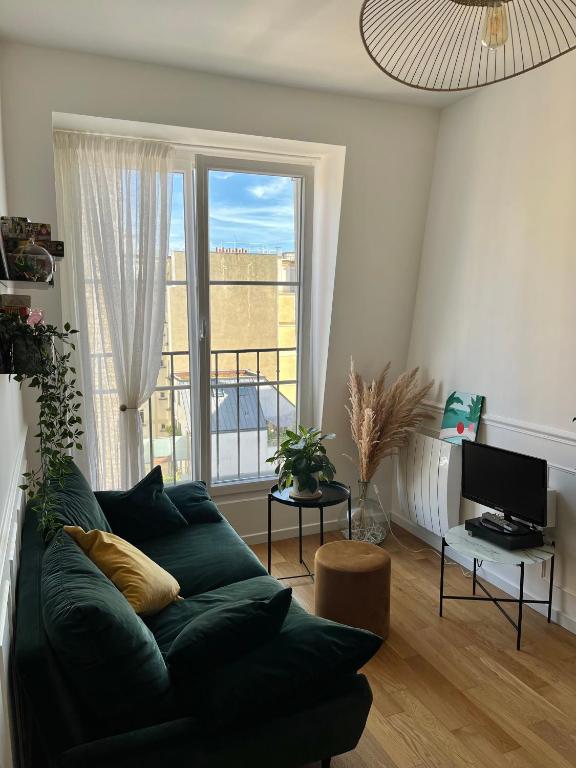 un salon avec un canapé vert et une fenêtre dans l'établissement Charmant deux pièces typiquement parisien, à Paris