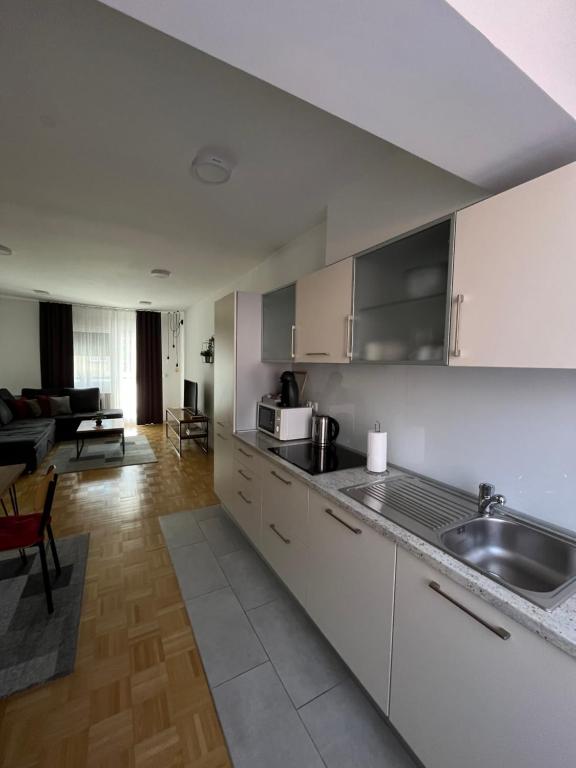een keuken met witte kasten en een woonkamer bij For5 in Ðakovo