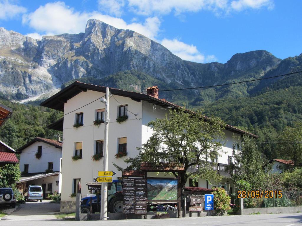 a white building with a mountain in the background at Rooms Pri Lovrižu in Kobarid