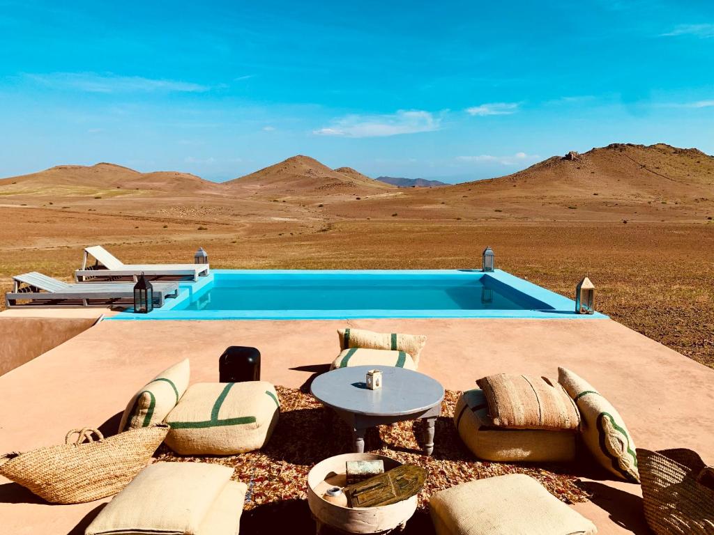 uma piscina no meio de um deserto com cadeiras e uma mesa em Lekechdomes la terre des bédouins em Jaïdat