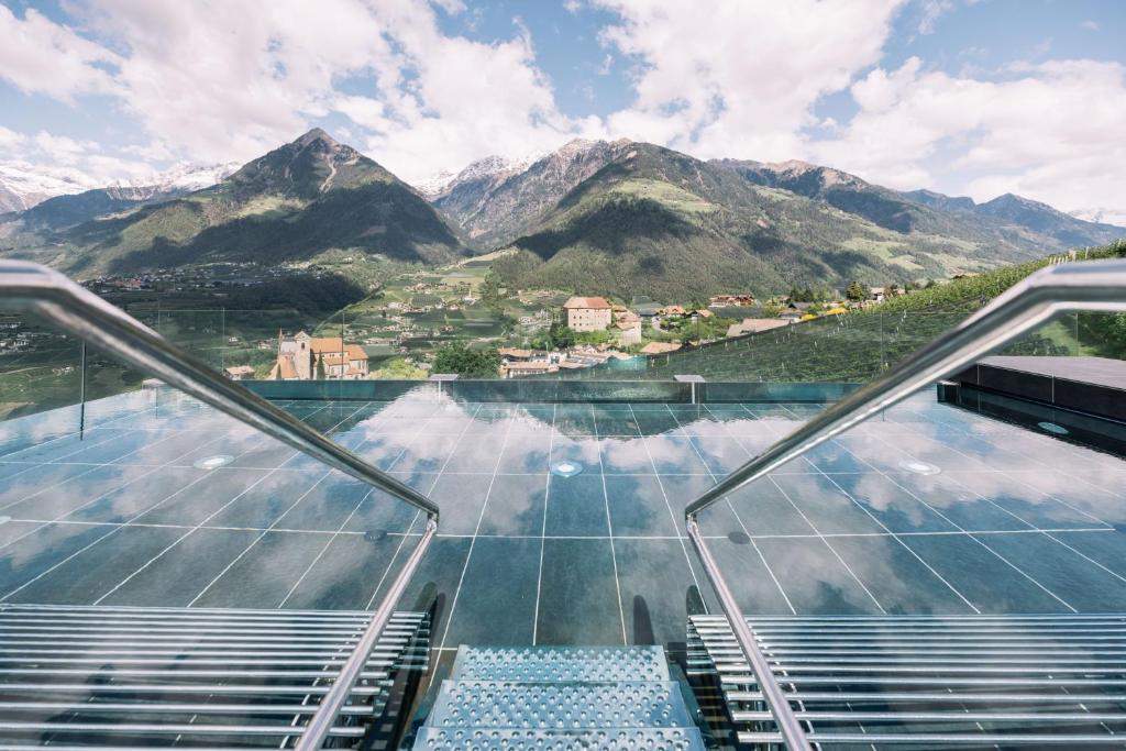 an observation deck on the glass floor of a building with mountains at Hotel Hohenwart in Schenna
