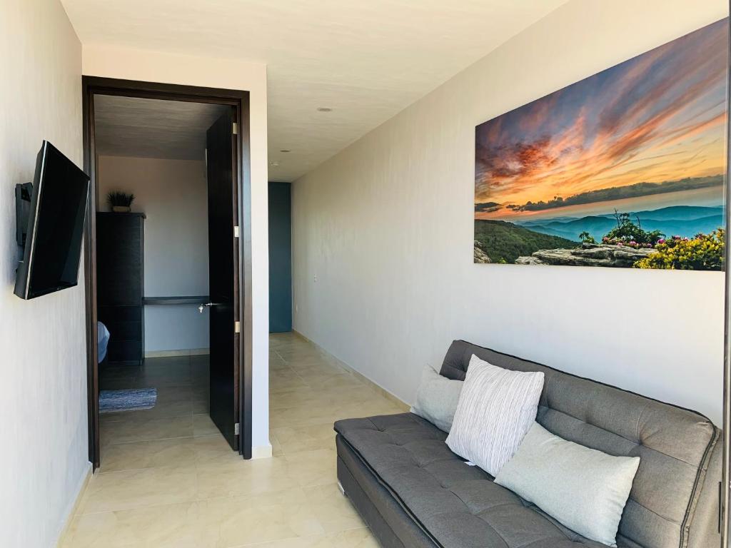 a living room with a couch and a painting on the wall at New Modern Condo with Air-condition in Zapotlanejo
