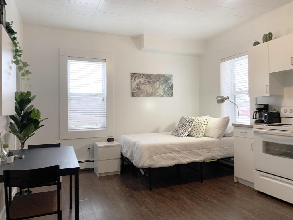 1 dormitorio pequeño con 1 cama y cocina en Cozy Bachelor Condo l Downtown l WiFi & Smart TV, en Moose Jaw