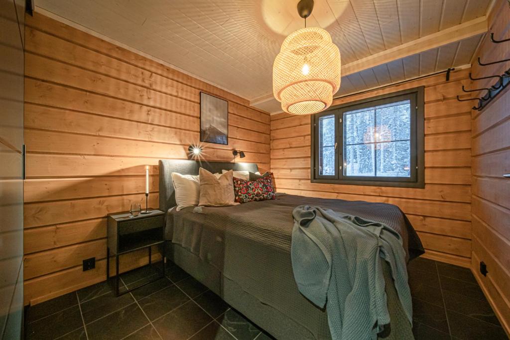 ein Schlafzimmer mit einem Bett in einem Zimmer mit Holzwänden in der Unterkunft Milis Chalet in Ylläsjärvi