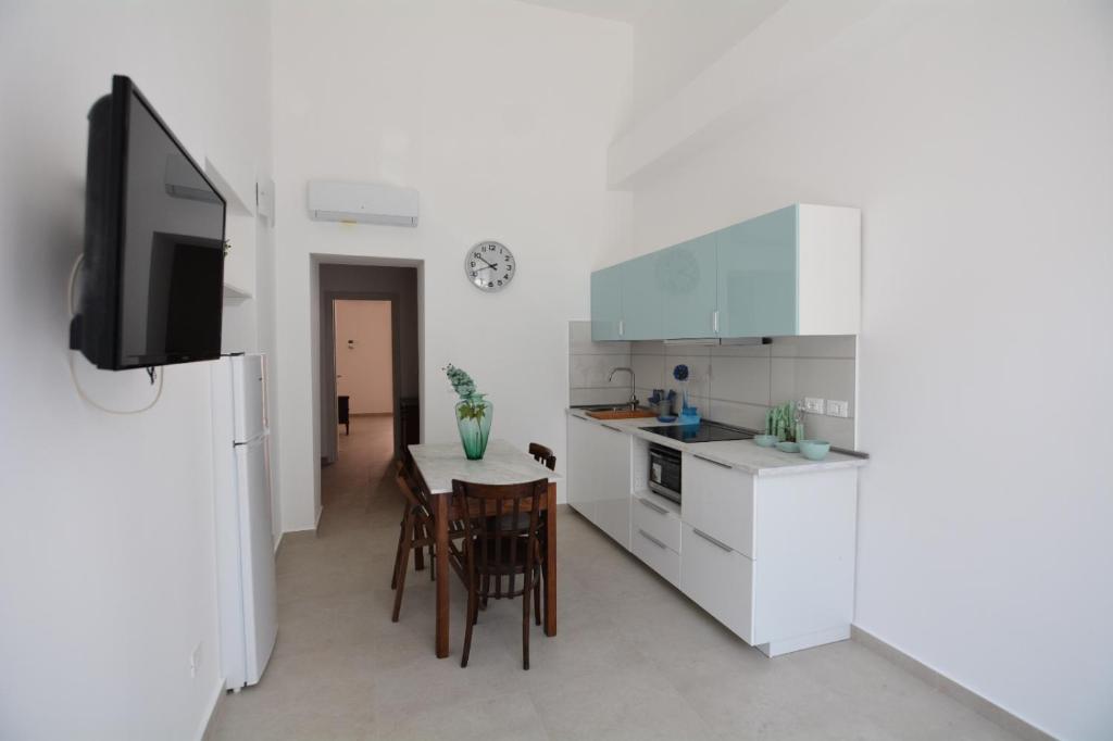 a kitchen with white cabinets and a table with chairs at Casa Ortensia in Santa Teresa di Riva