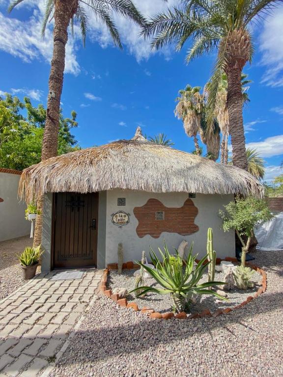 a small building with a thatched roof and palm trees at Studio Candelero en Loreto in Loreto