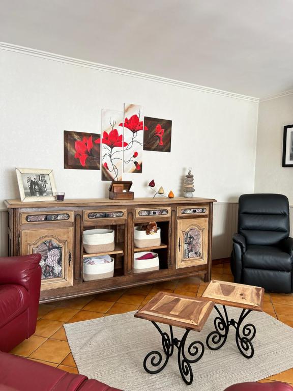 ein Wohnzimmer mit einem Holzschrank und einem Stuhl in der Unterkunft Maison bord de Marais proche Plage du Débarquement in Auvers