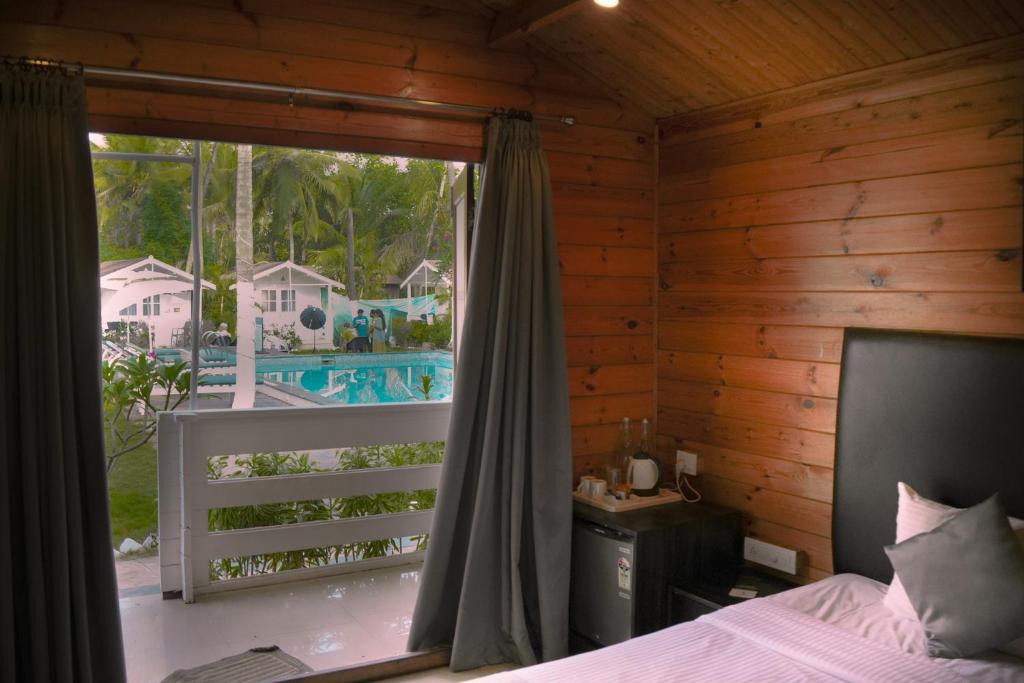 a bedroom with a bed and a window with a view of a pool at Seawood beach front resort in Morjim