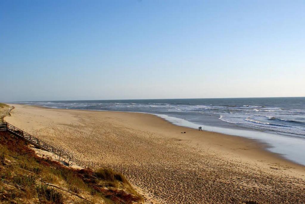 une plage de sable avec l'océan en arrière-plan dans l'établissement APPARTEMENT COEUR DE LA STATION, à Mimizan