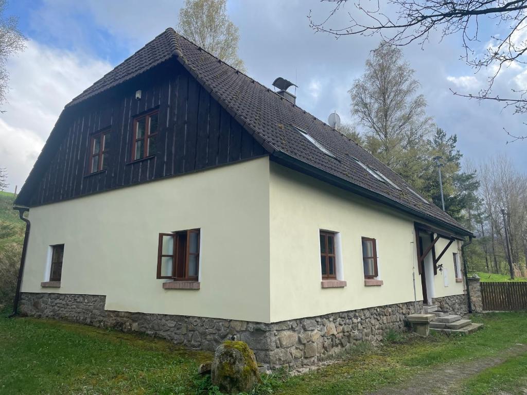 uma casa branca e preta com um telhado preto em Hájovna u Jezerního potoka em Nová Pec