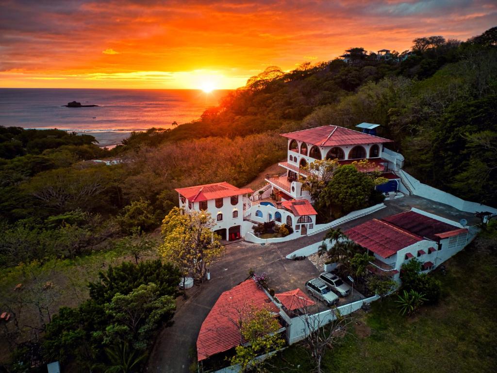 una vista aérea de una casa con la puesta de sol en el fondo en Beachside stay at Villa ViYarte, en San Juan del Sur