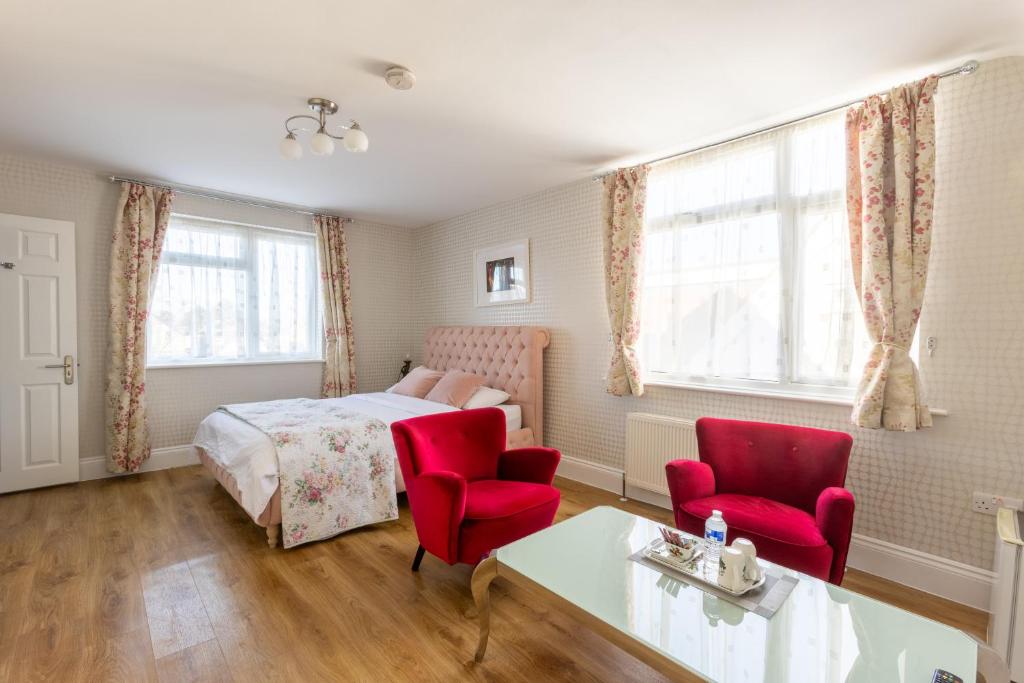 a bedroom with a bed and two red chairs at Katolondonhaus in Mitcham