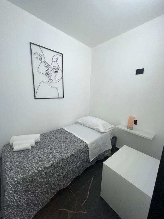 a small white room with a bed and a table at Casa Vacanze Donna Sidora in Palermo