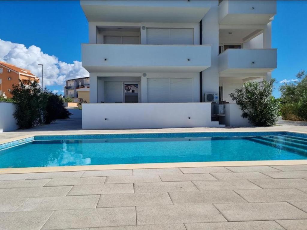 a house with a swimming pool in front of a building at Villa Sunny Day Sendi Deluxe - Novalja in Novalja