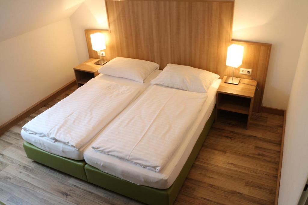 a large bed in a hotel room with two lamps at Gasthof Kranerwirt in Lannach