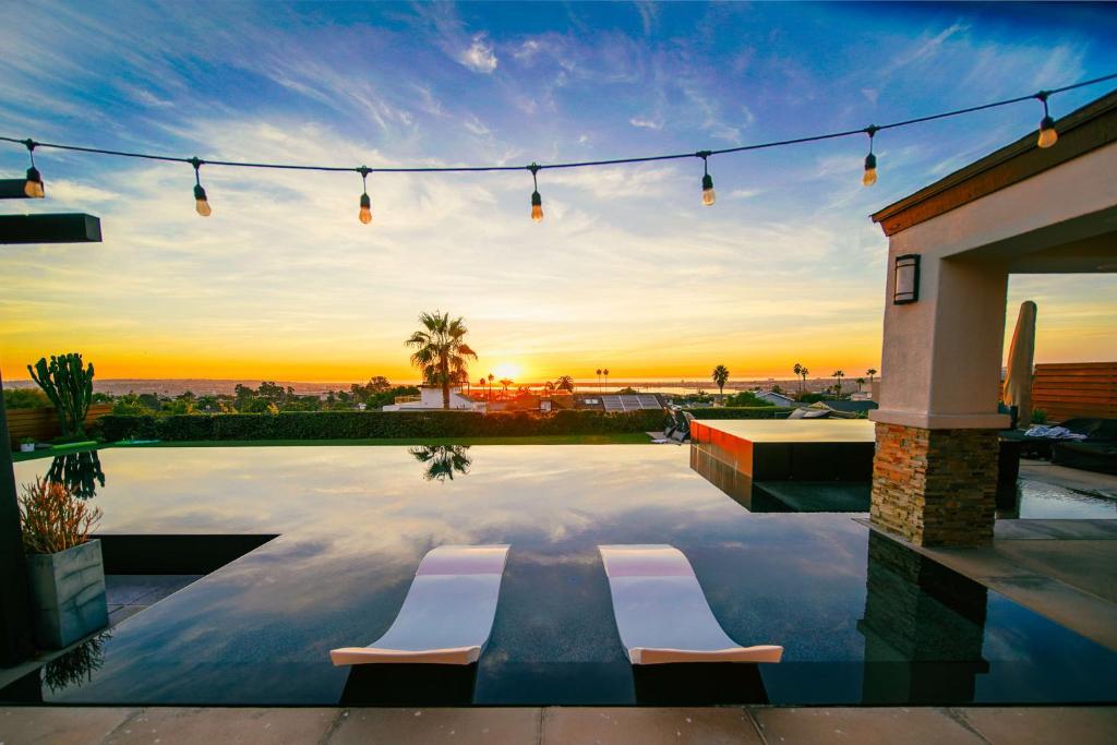a pool with two chairs and a sunset in the background at Panoramic Ocean sunset Views with Heated Pool & Spa best location in San Diego
