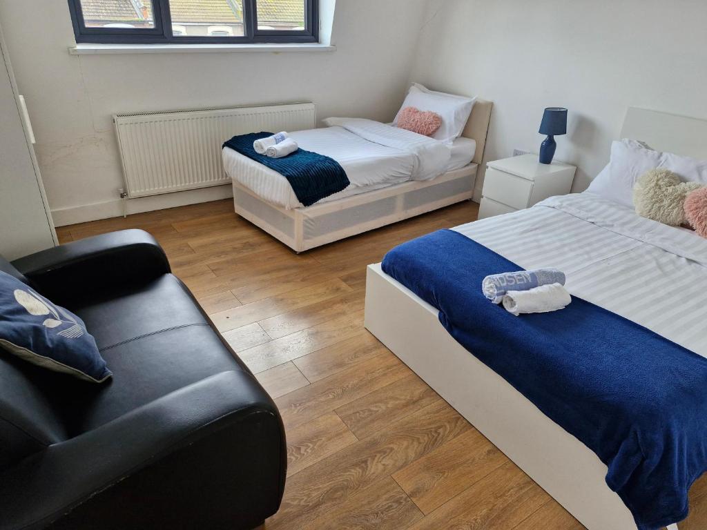a bedroom with two beds and a couch in it at Simply Relax, Eastham London in London