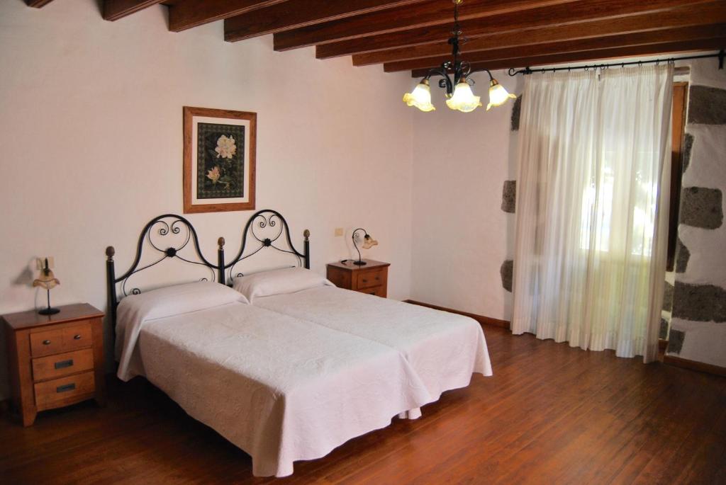 a bedroom with a bed with white sheets and wooden floors at Casa Rural Los Suárez in Agüimes