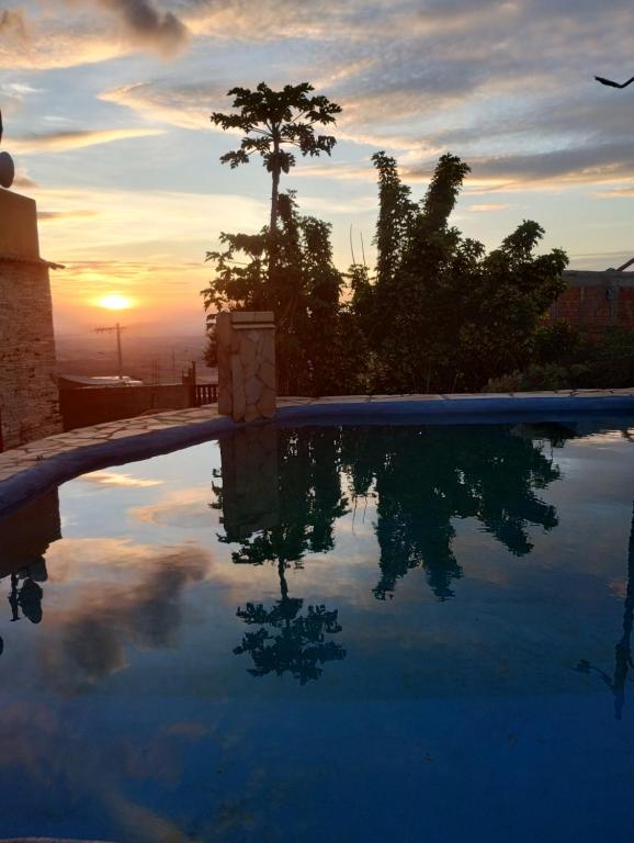 a swimming pool with the reflection of the sunset at Recanto das Pedras Hospedagem in São Thomé das Letras