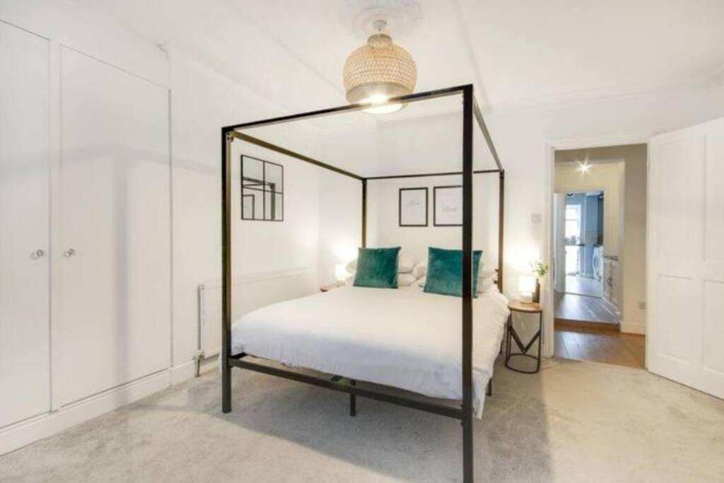 a bedroom with a canopy bed with green pillows at Central 2 bedroom garden flat with free parking in Royal Tunbridge Wells