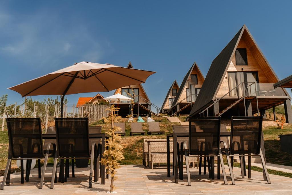 a table and chairs with an umbrella and houses at CAVO VILLAGE- Cabins Rental Băile 1 Mai in Rontău