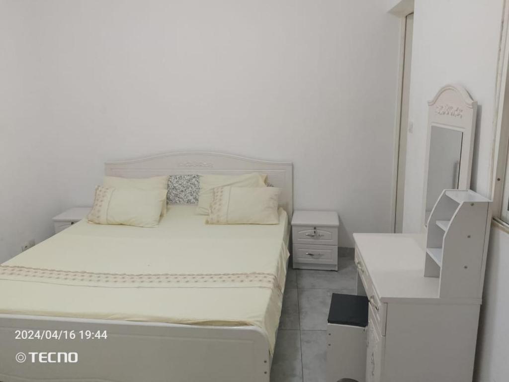 a white bedroom with a bed and a dresser at Appartement entier F3 climatisé agréable, spacieux et confortable à Gadaye in Dakar