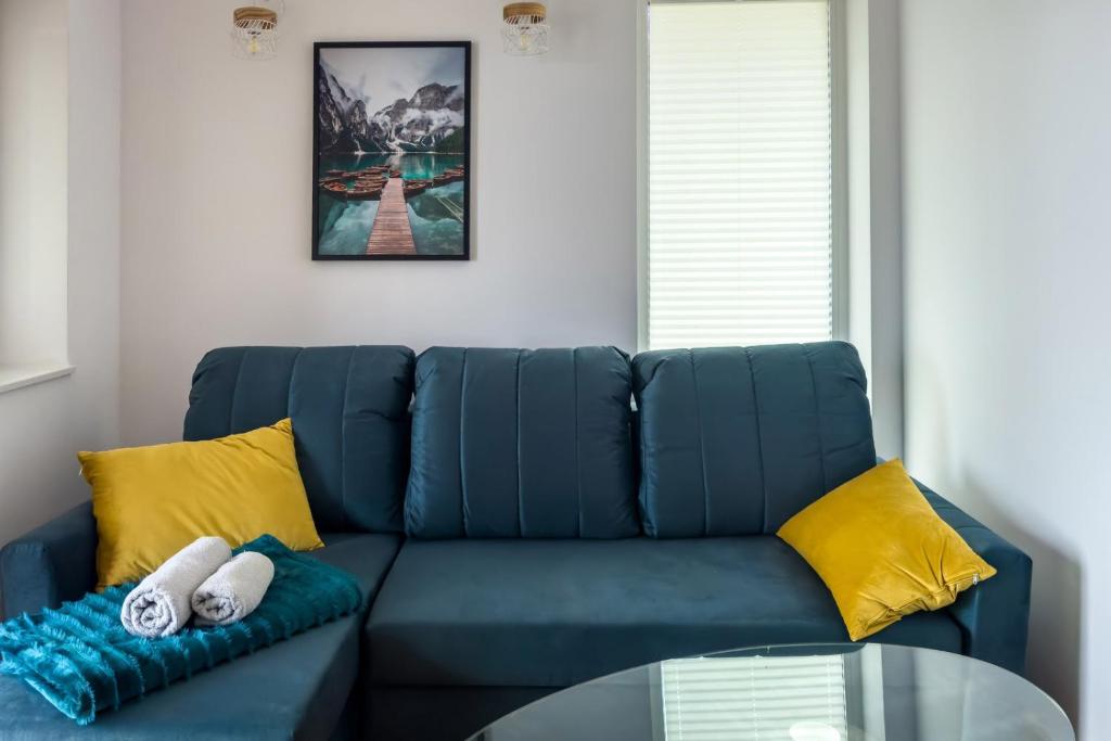 um sofá azul com almofadas amarelas e uma mesa de vidro em NORDHOUSE II em Jastrzebia Gora