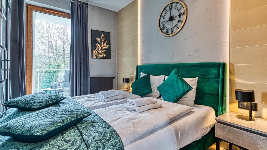 1 dormitorio con cama verde y reloj en la pared en LOFT MOUNTAIN Apartament Szklarska Poręba, en Szklarska Poręba