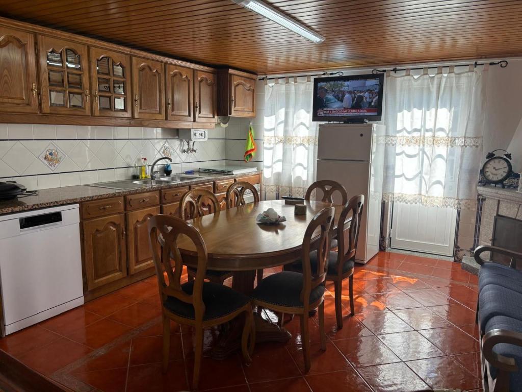 a kitchen with a table and chairs and a television at White House in Piódão