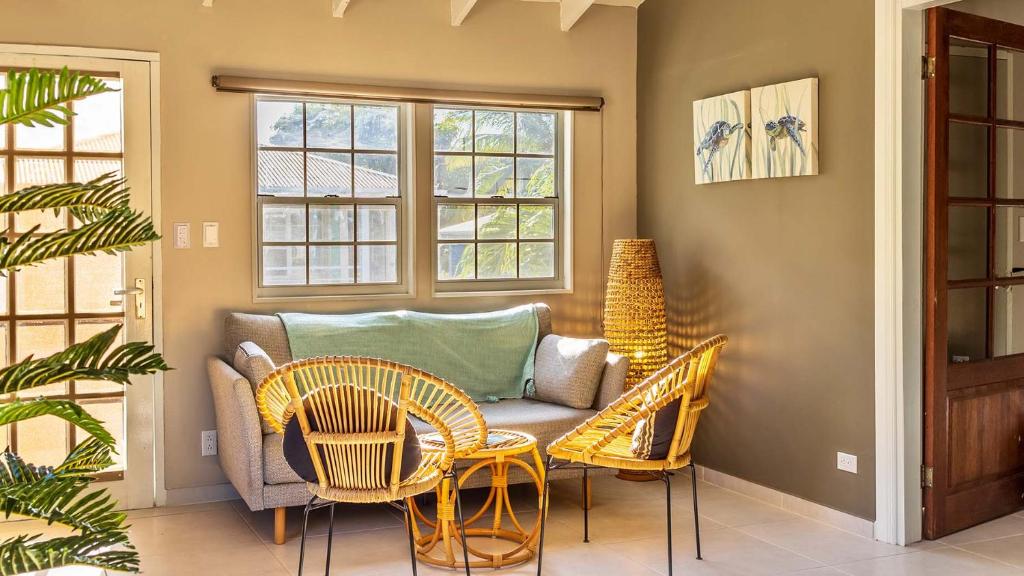 a living room with a couch and chairs and windows at Talk of the Town Inn & Suites - St Eustatius in Oranjestad