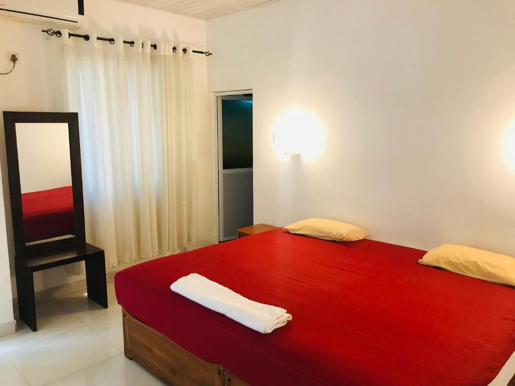 New hotel canel park في بولوناروا: غرفة نوم بسرير احمر كبير ومرآة