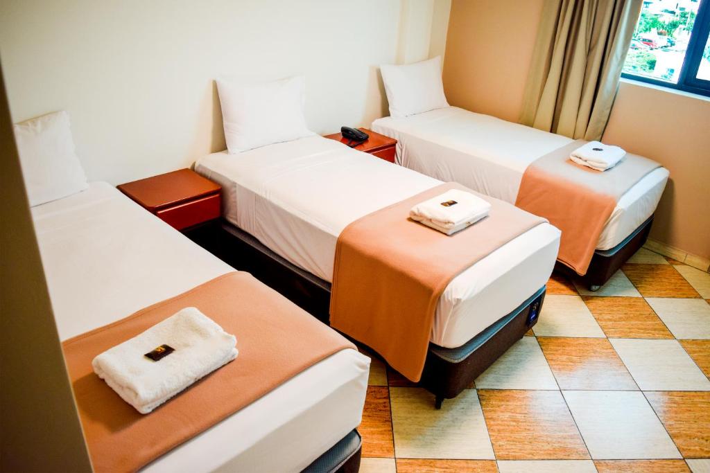 una habitación de hotel con 3 camas en una habitación en Hotel Mega, en Lima