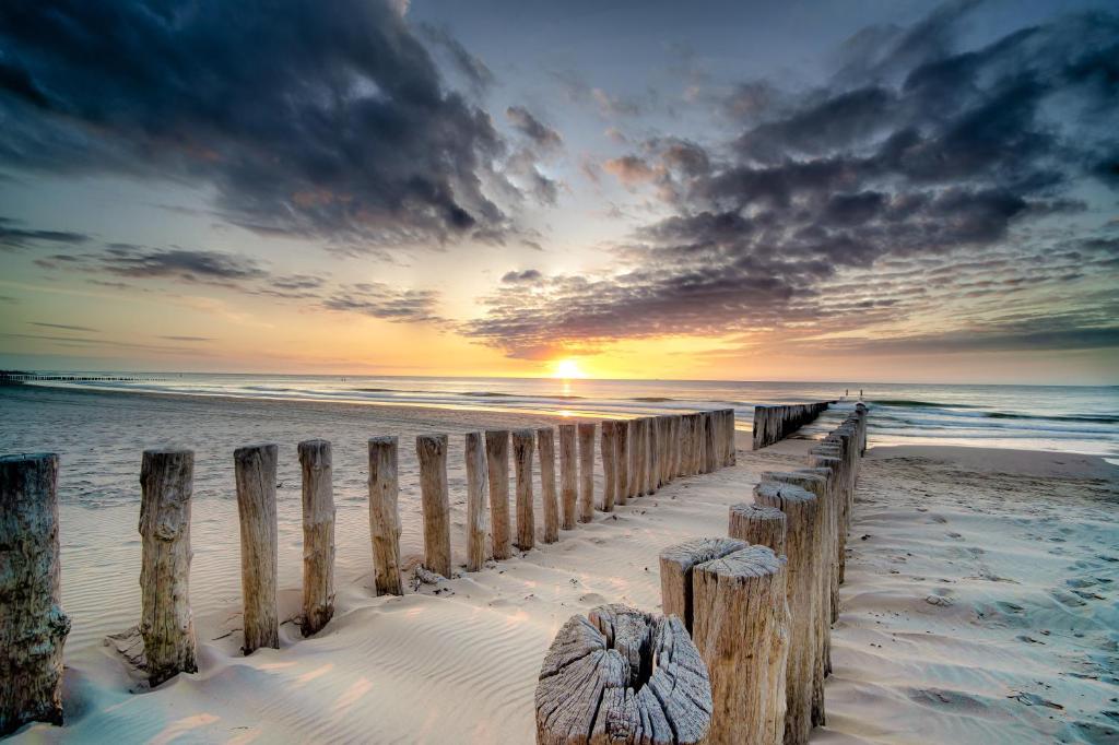 a sunset over the beach with a wooden pier at Ostsee Ferienhaus mit Whirlpool in Wolgast