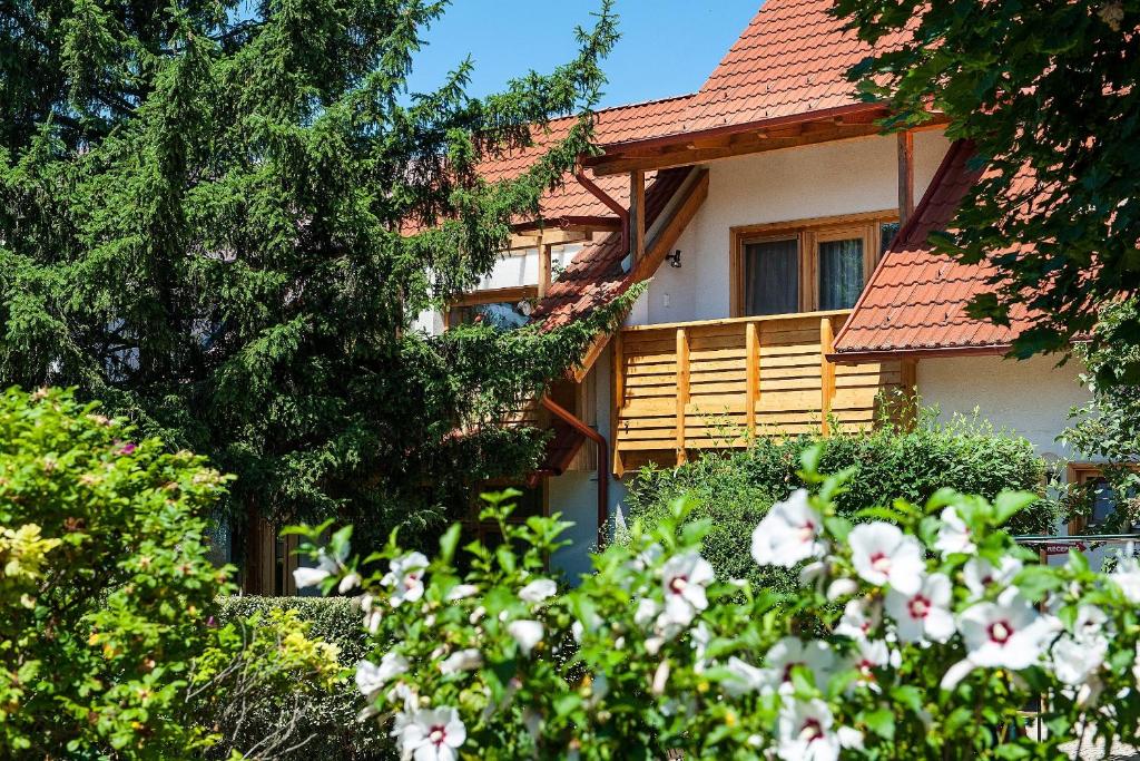 une maison avec des arbres et des fleurs devant elle dans l'établissement ALina Apartmanház, à Hévíz