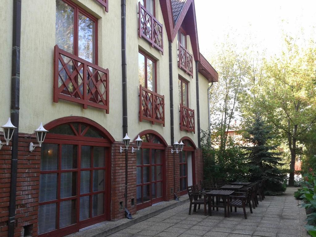 a building with red doors and a patio with tables at Bed Breakfast Hotel Budapest in Budapest