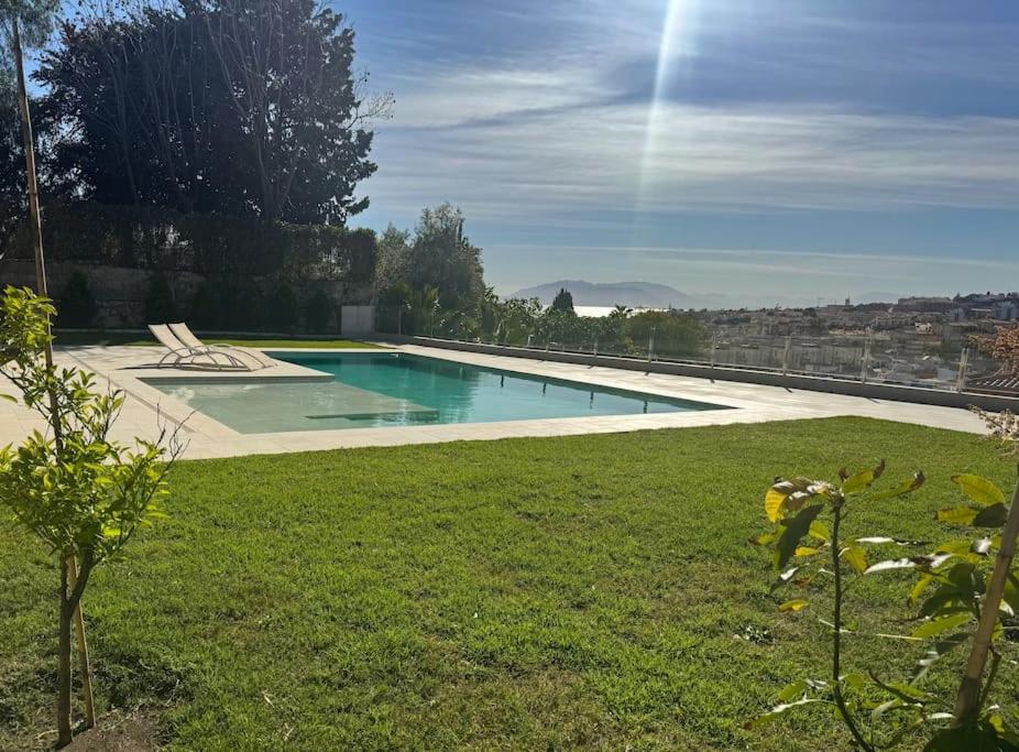 een zwembad in een tuin met een groen gazon bij apartamento piscina privada in Rincón de la Victoria