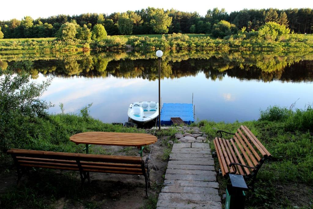 dos bancos y una mesa y un barco en un lago en Kentavr Hotel, en Navapolatsk