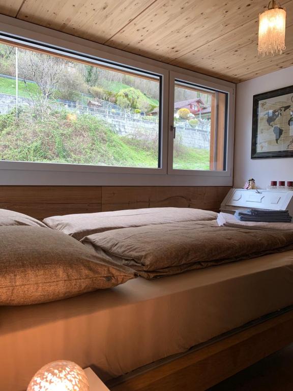 a bedroom with a bed and two windows at Lina - Lakeview Living near Interlaken in Niederried