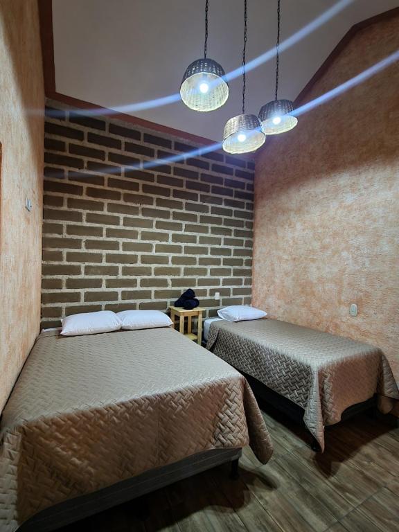 een kamer met 2 bedden en een bakstenen muur bij Central Hostel Boutique in Antigua Guatemala