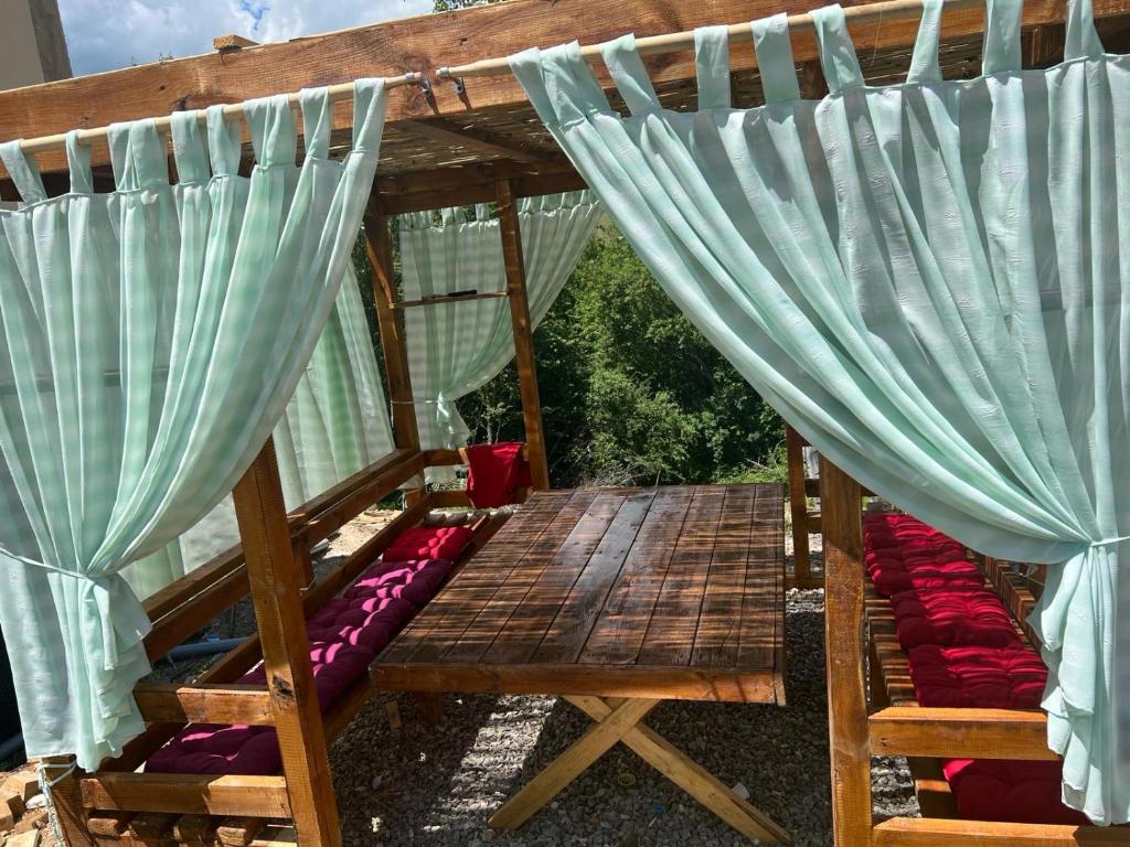 a pergola with two beds with blue curtains at Etno selo Raj na Uvcu in Sjenica