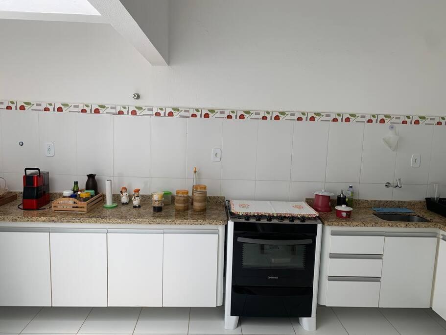 eine Küche mit weißen Schränken und einem schwarzen Backofen in der Unterkunft Casinha da Paz in Aracaju