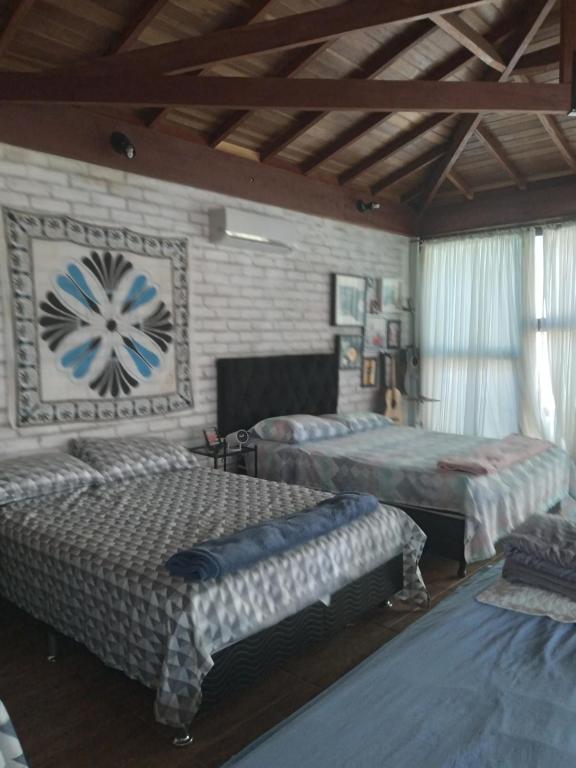 a bedroom with two beds and a brick wall at casa rústica e aconchegante in Analândia